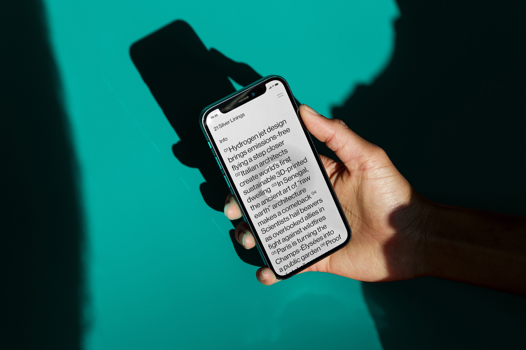 Hand holds smartphone displaying article snippets on design, architecture, and environmental topics against a teal-green background.