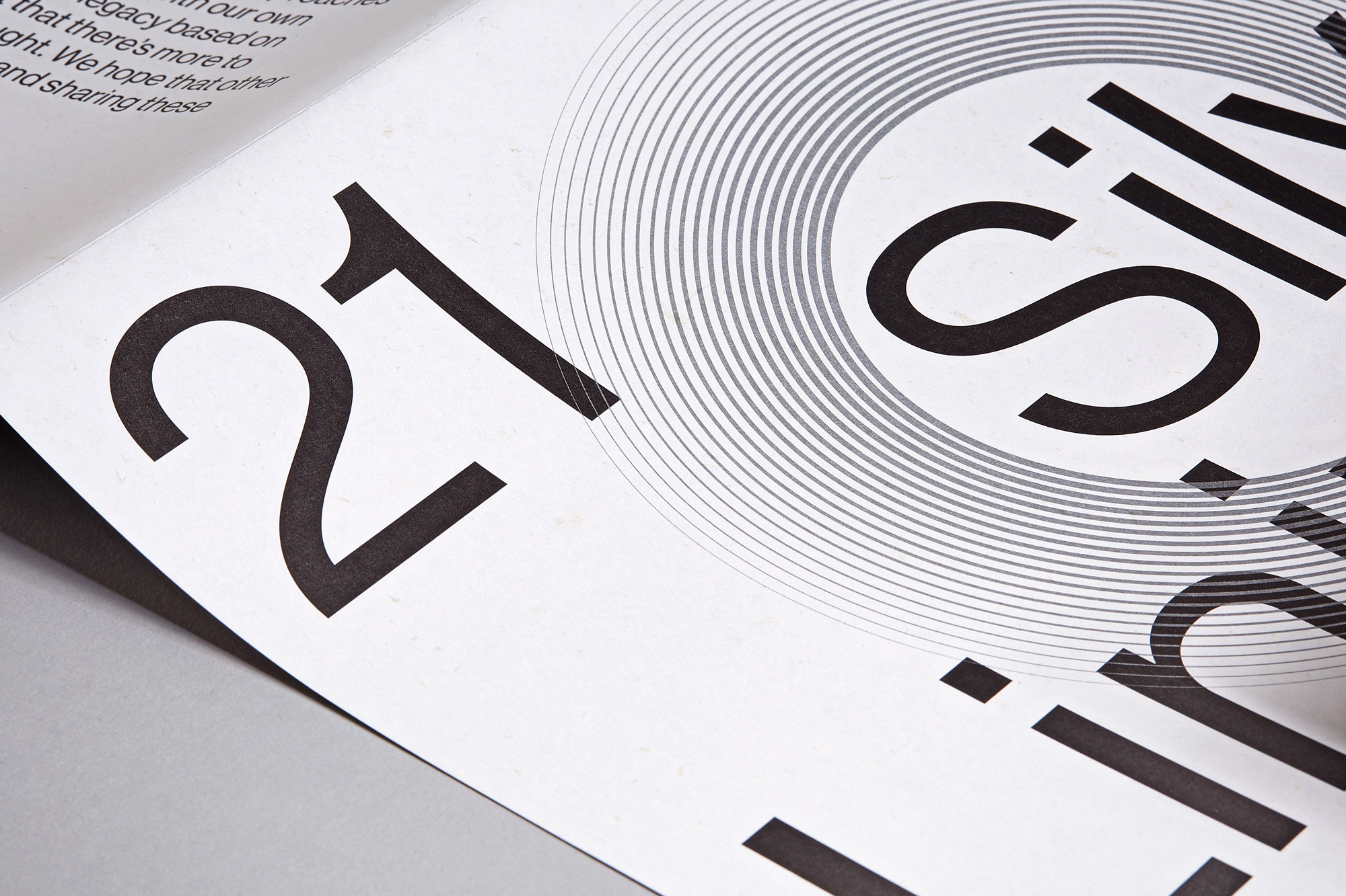 Macro shot of black typography '21' and part of the word 'Silverlining' on white pages with concentric circles design element.