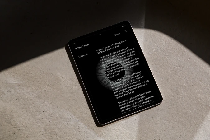 Digital tablet on textured surface displaying graphic design publication titled '21 Silver Linings' focused on climate change solutions.