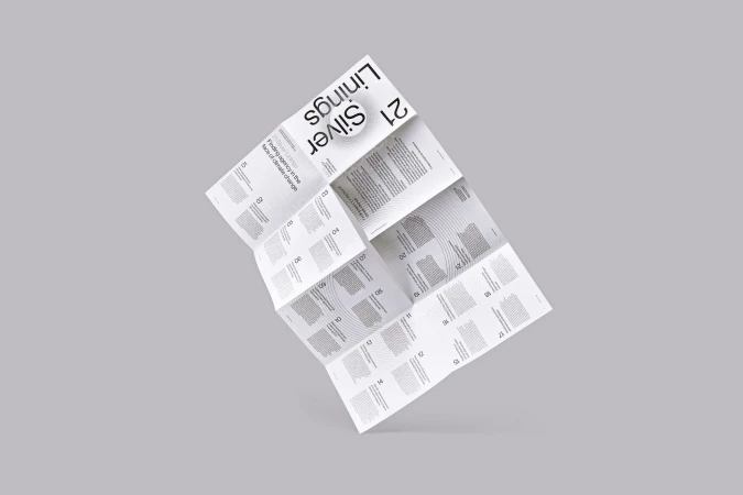 Folded printed publication titled Silver Linings floating against a neutral grey studio backdrop