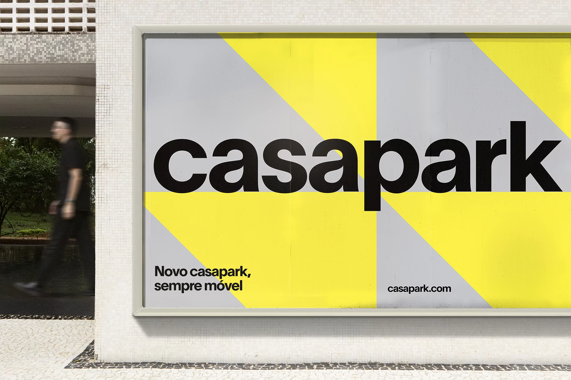 Casapark ad on a building exterior with a pedestrian walking by. The ad features a yellow and gray geometric background.