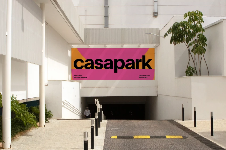 Exterior of a building with a 'casapark' advertisement sign above a parking entrance, featuring modern architecture and lush greenery.