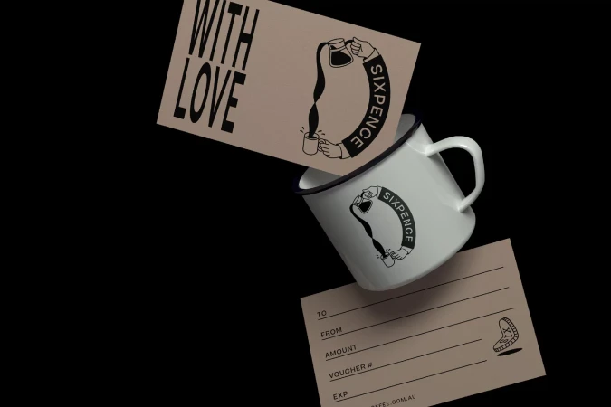 A white enamel mug with the Sixpence logo alongside a gift card that says "With Love" against a solid black background.