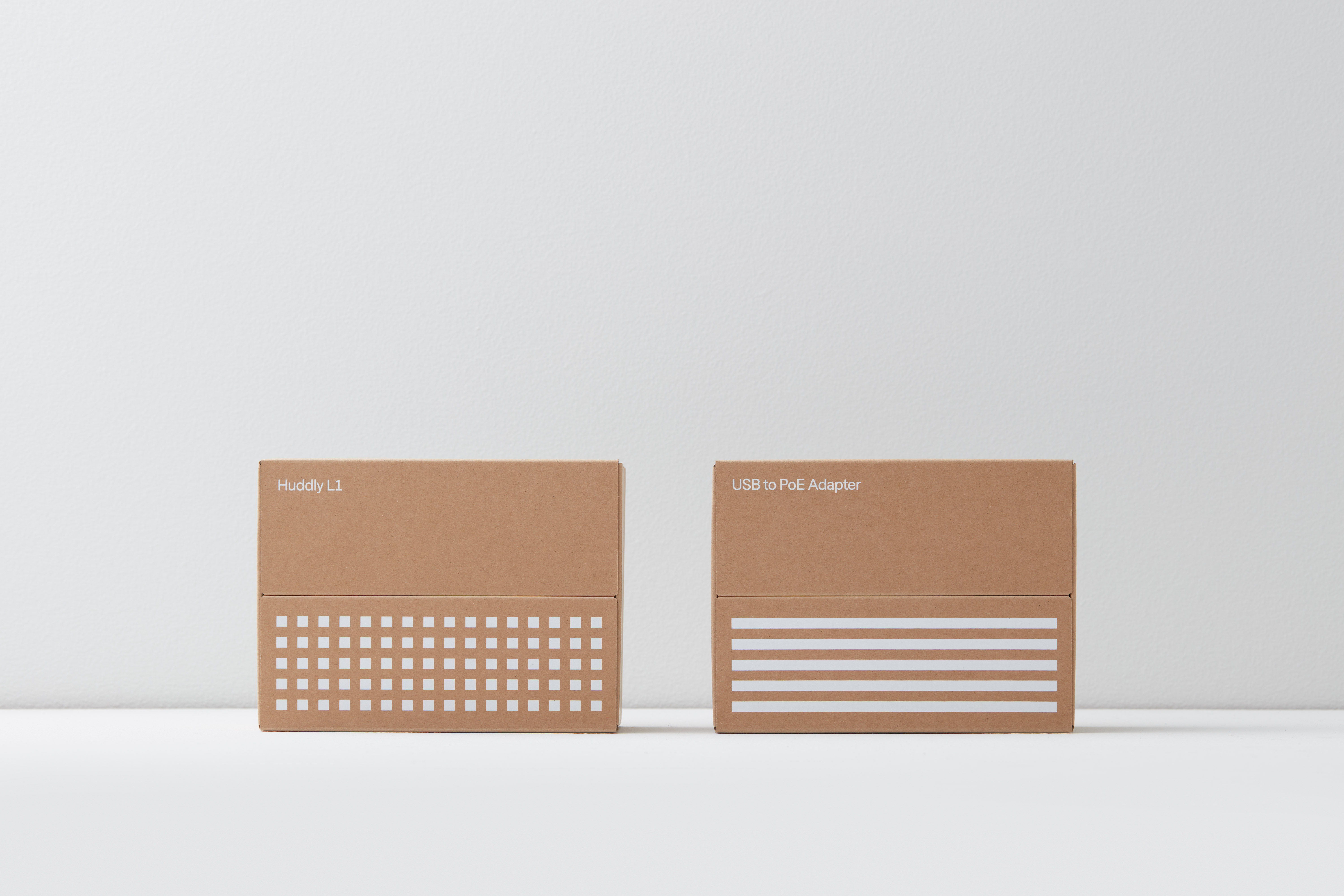 Two brown cardboard boxes with white printed graphics set against a clean white seamless studio background.
