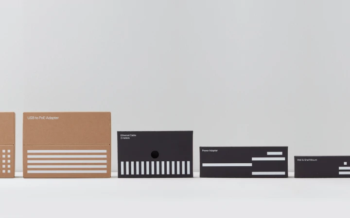A row of product boxes for electronic accessories, featuring a mix of kraft and black boxes with white text and linear designs.