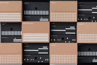 Arrangement of Huddly brand packaging boxes featuring brown cardboard and black covers with white graphic patterns and typography