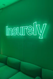 Insurely green neon sign mounted on a matching green wall above a sectional sofa