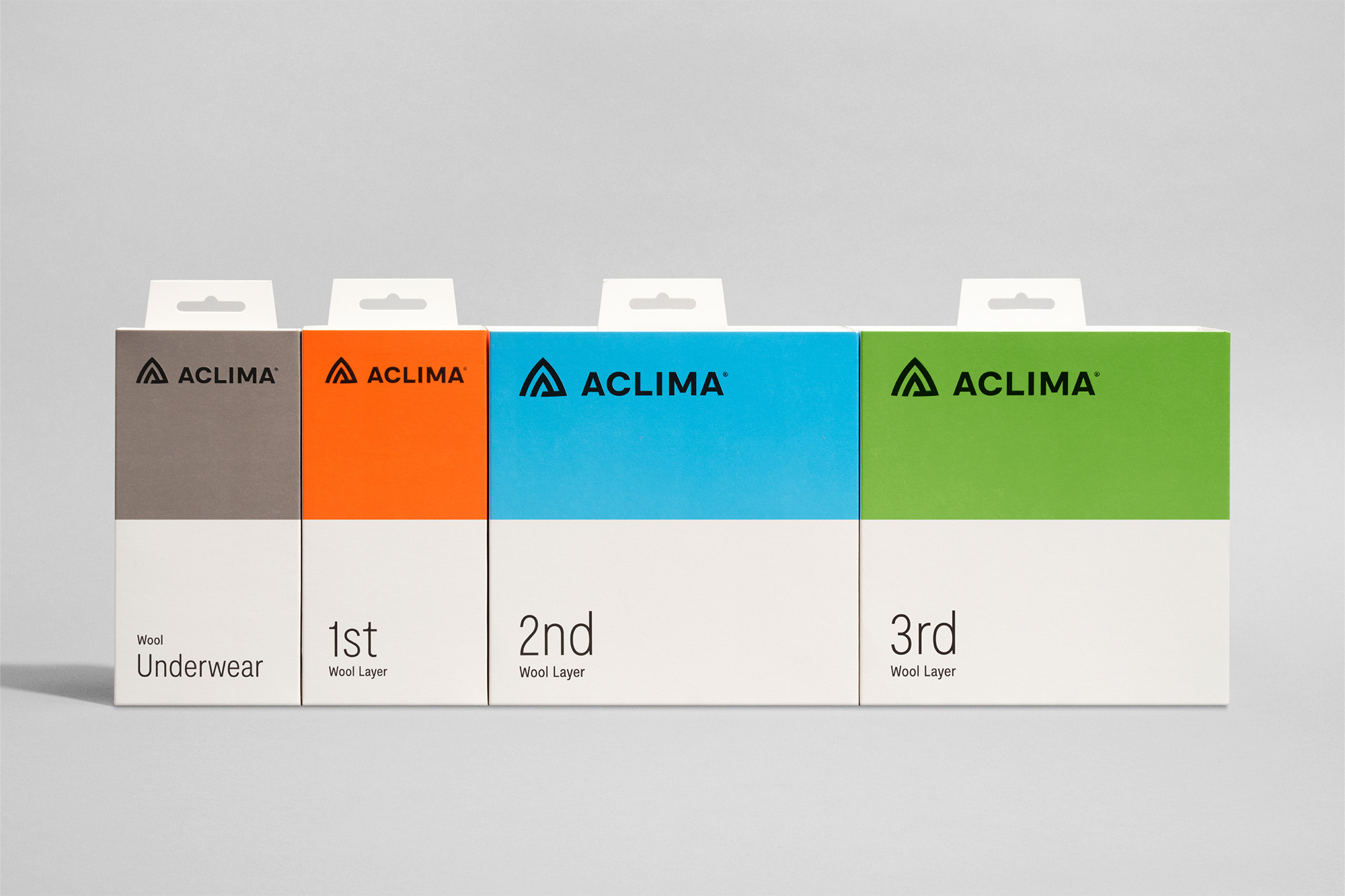 Four ACLIMA wool base layer boxes in gray, orange, blue, and green, displayed side by side against a solid white background.
