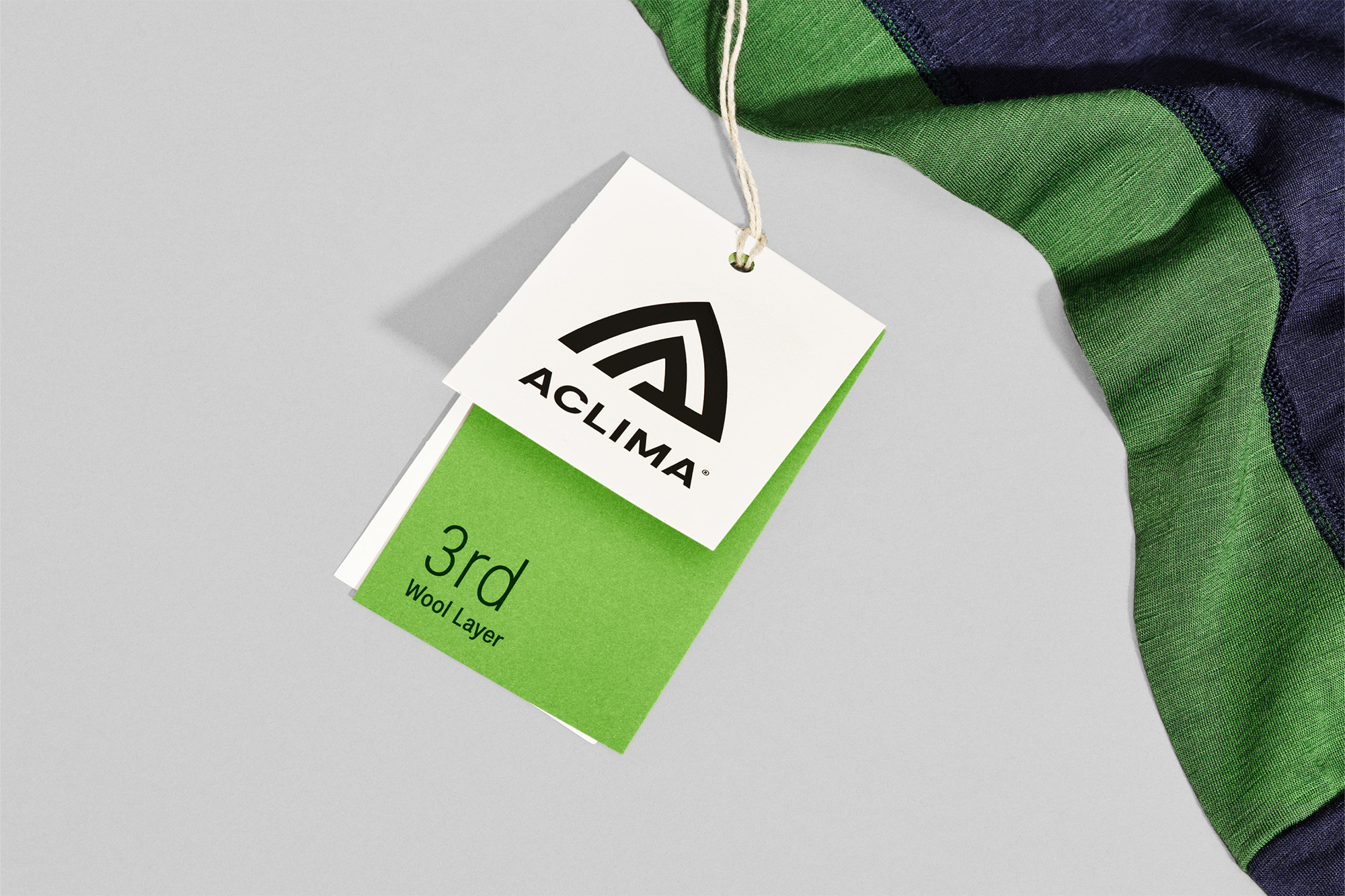 Close-up of an Aclima clothing tag, showcasing the brand logo and product information against a neutral background with apparel.