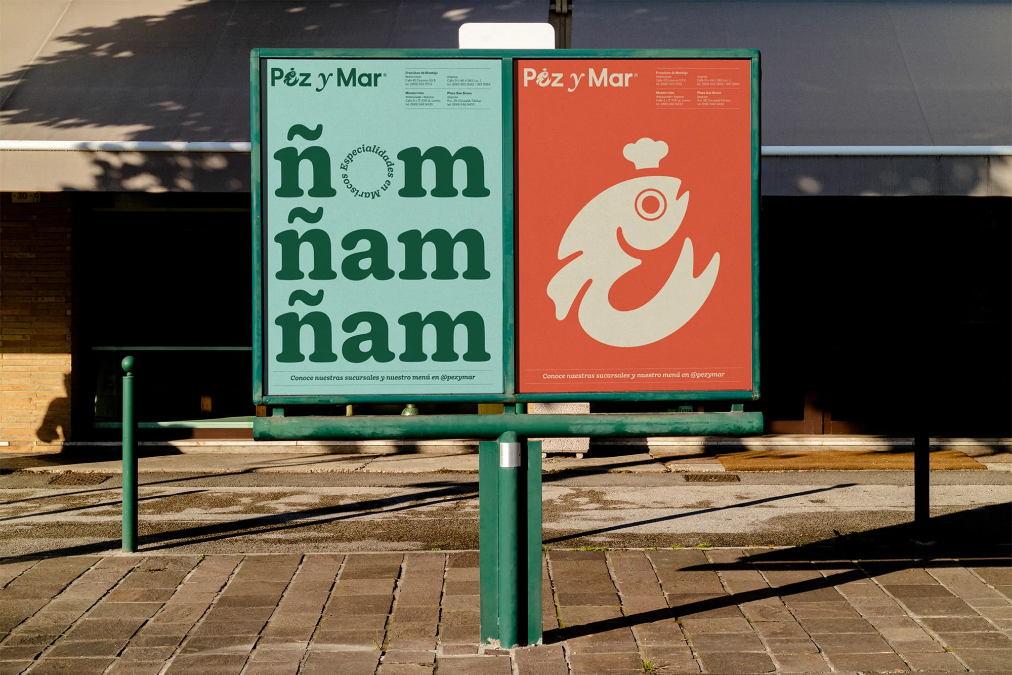 Two posters advertise 'Pez y Mar' seafood restaurant with graphic fish design and bold typography on a green metal frame outdoors.