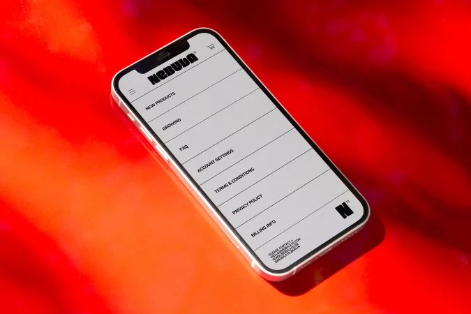 A smartphone displays a website menu against a vibrant red backdrop, creating a modern and tech-focused visual with a glossy sheen.