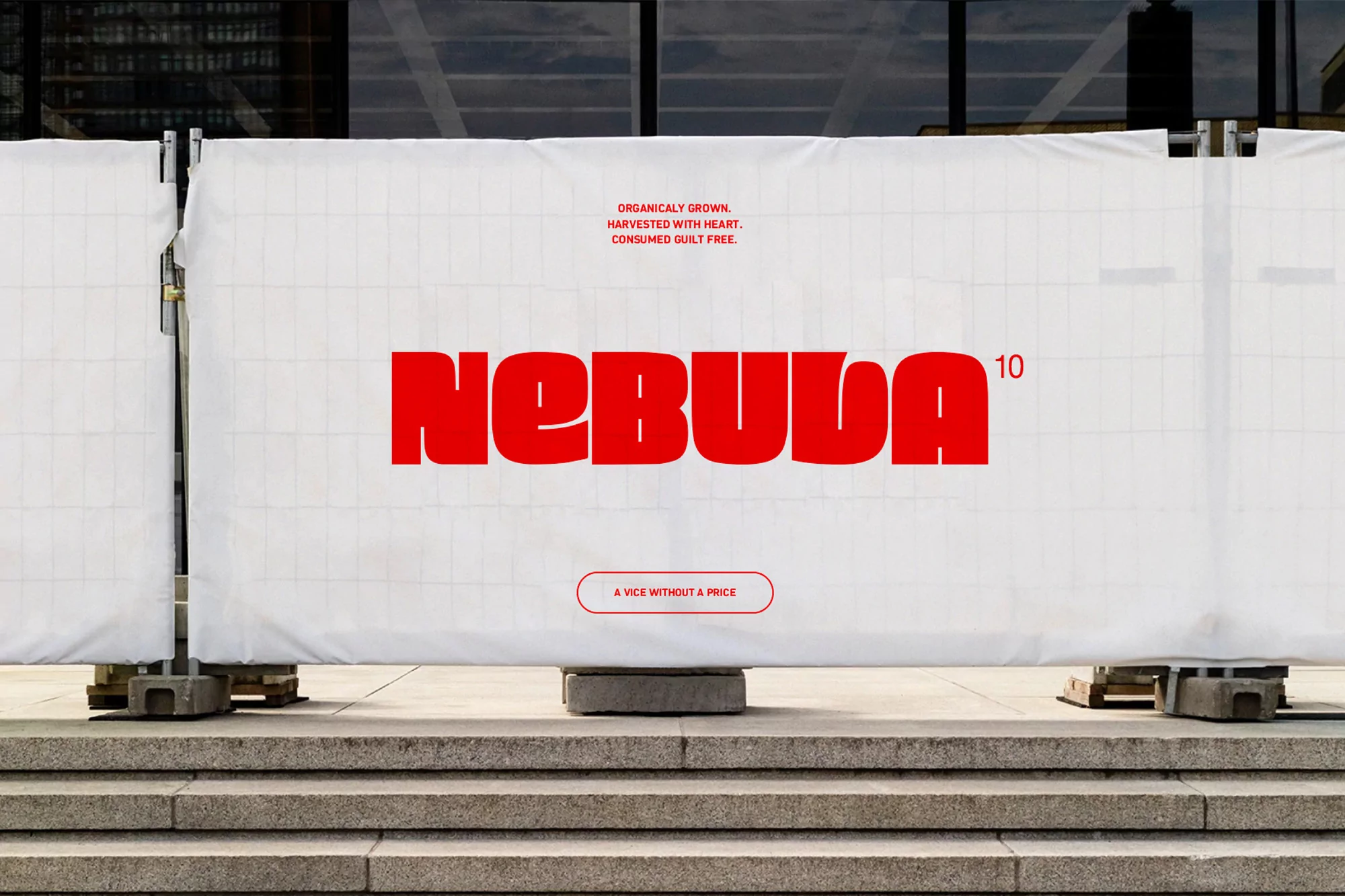 Red 'Nebula' logo with the tagline 'A Vice Without a Price' printed on a white temporary fence on a concrete surface outside.