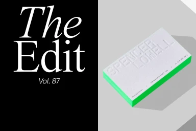 White business card with embossed name and green painted edge on grey background next to black panel with white text