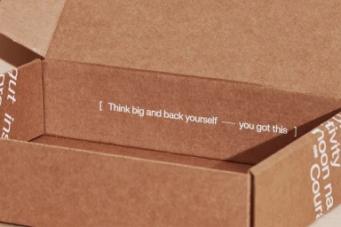 Open brown cardboard mailer box featuring white printed typography on the interior panels.
