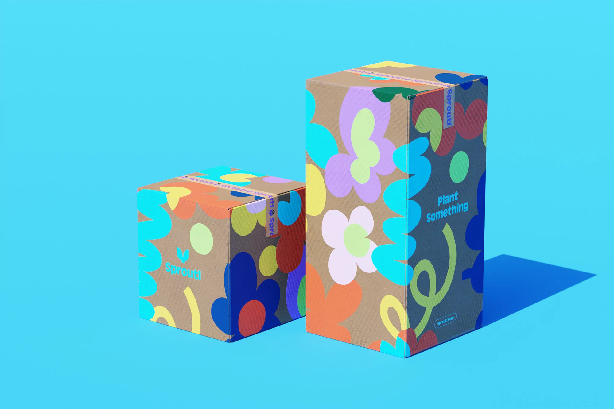Two cardboard boxes with colorful floral and text patterns sit on a light blue surface, with the larger box slightly taller.