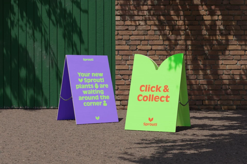 Two A-frame signs on a gravel surface. One is purple, the other is lime green, with 'Sprouti' branding and plant purchase message.