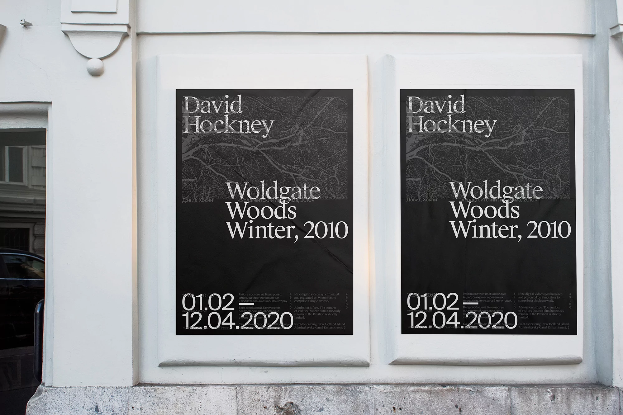 Two posters of David Hockney's Woldgate Woods Winter, 2010 exhibition are mounted on a white wall, capturing artistic expression and promotion.