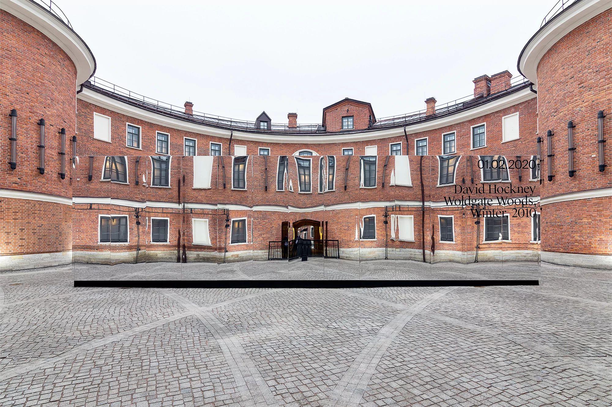 Artistic panorama view of a brick building with repeating window patterns, showcasing architectural details and cobblestone courtyard.