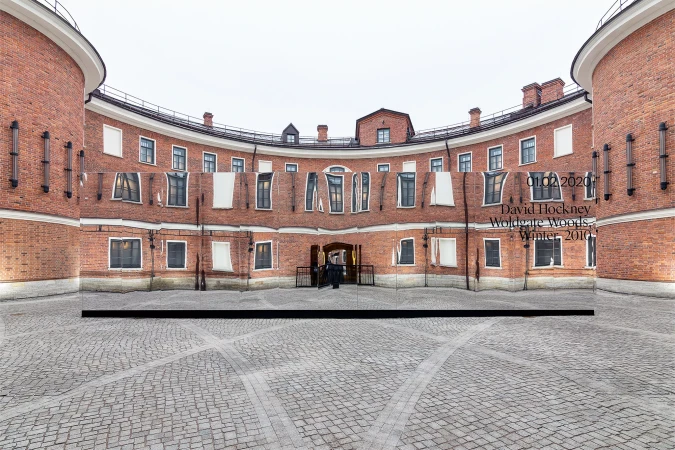 Artistic panorama view of a brick building with repeating window patterns, showcasing architectural details and cobblestone courtyard.