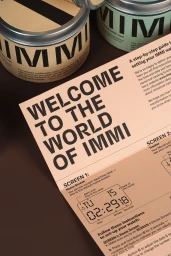 Close-up product packaging and instruction card for IMMI brand identity featuring bold typography on tan paper.