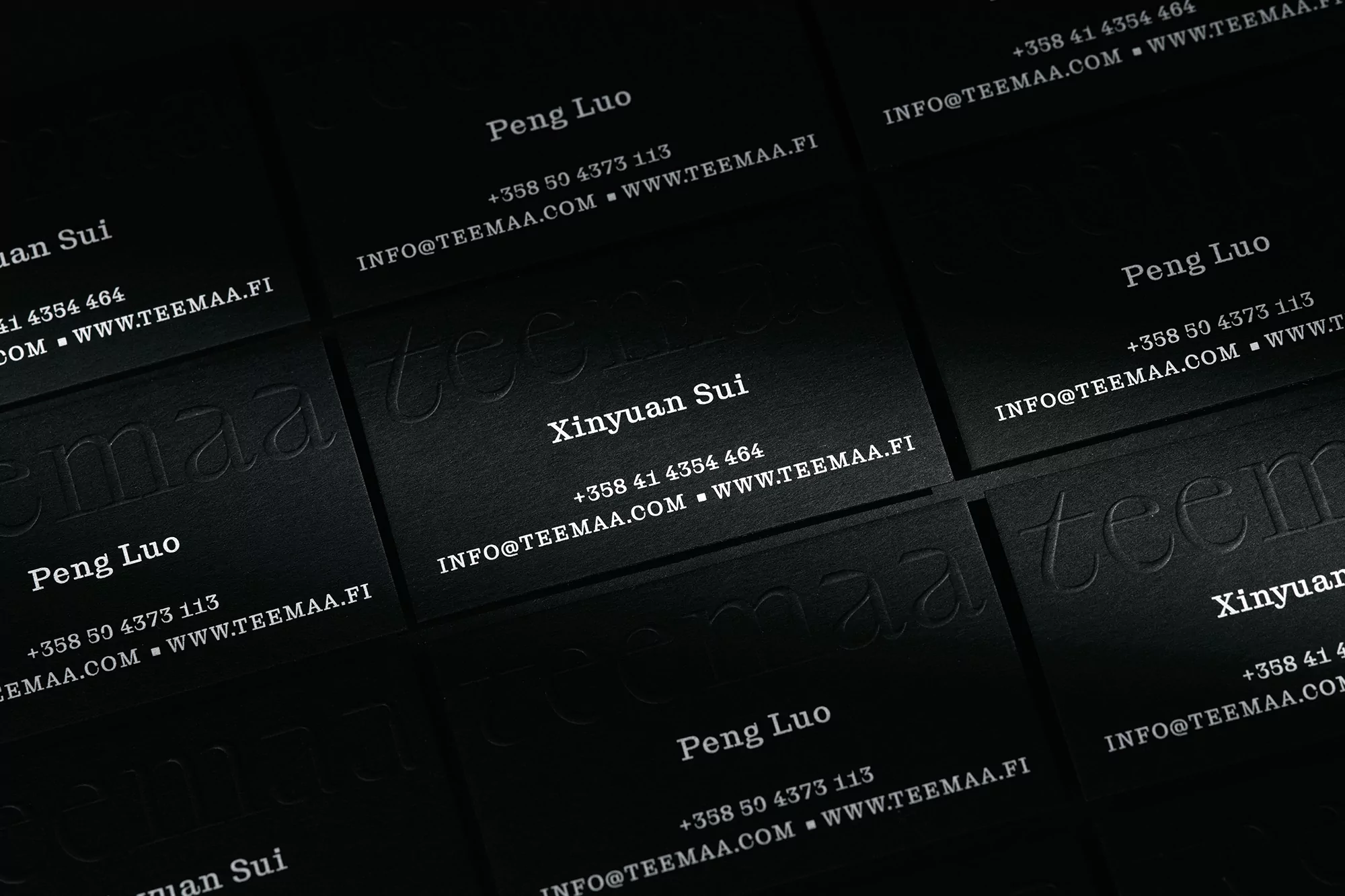 Several black business cards with white text, displaying contact information and names, arranged at a slight angle.