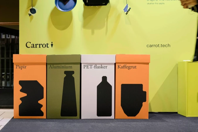 Colorful recycling station featuring separate bins for paper, aluminum, plastic (PET-flasker), and coffee grounds (Kaffegrut).