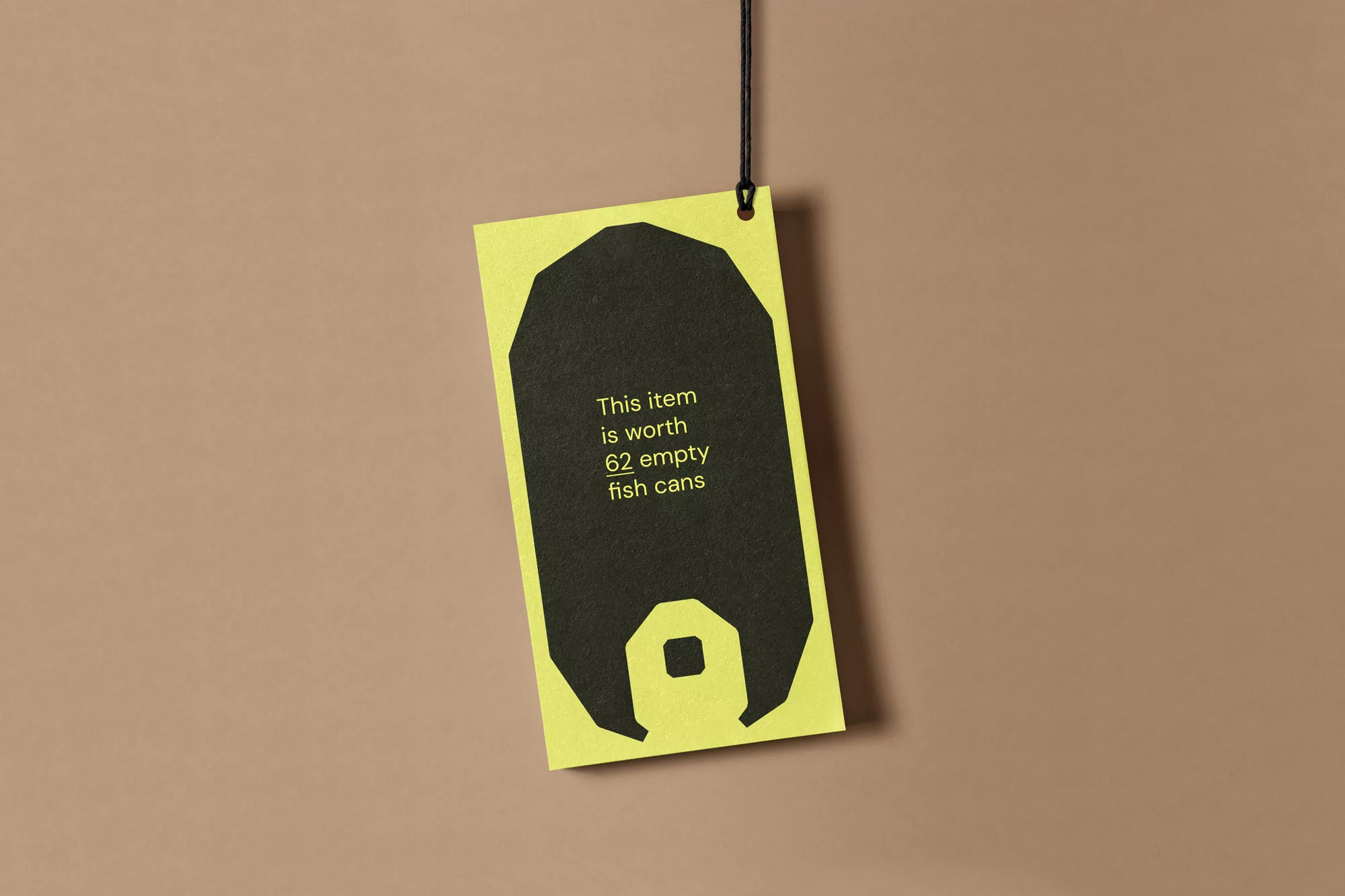 A yellow tag suspended by a black string against a neutral background. The tag features a dark graphic and text: 'This item is worth 62 empty fish cans'.