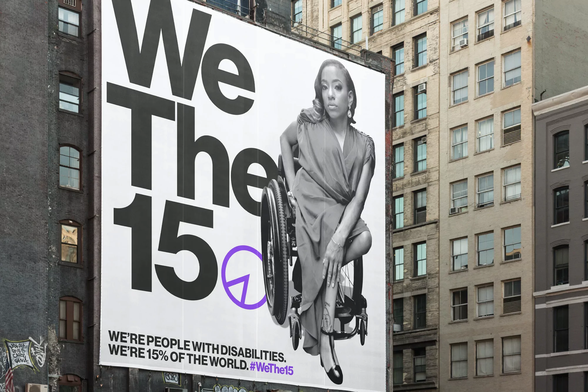 Billboard features a woman in a wheelchair, set against an urban backdrop, with the slogan 'We The 15' promoting disability awareness.