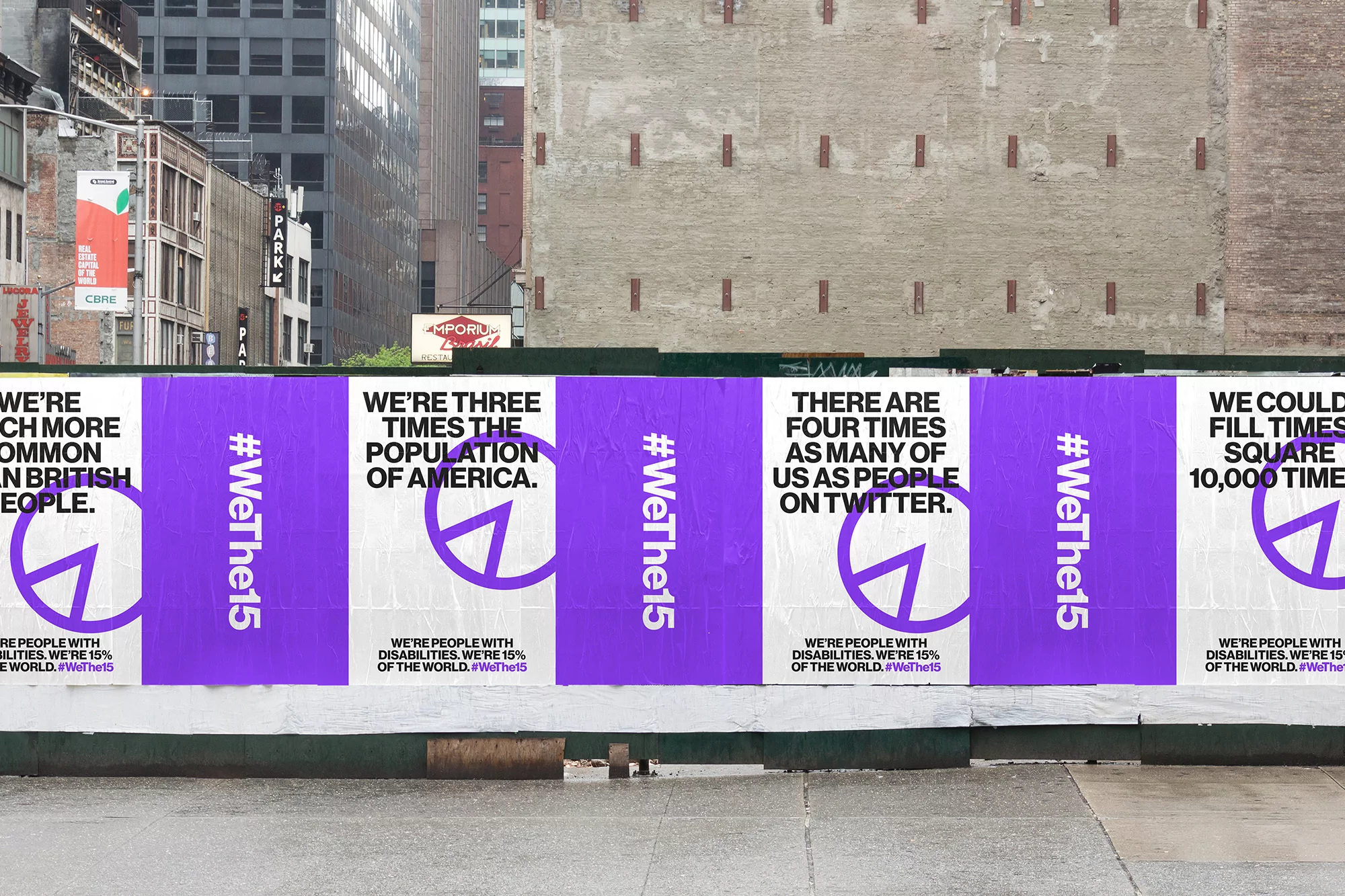 Eye-level close-up shows WeThe15 disability awareness posters on urban barriers, featuring purple peace sign variants and block text.