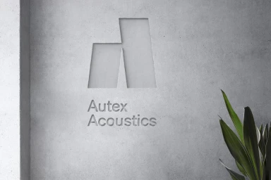 Autex Acoustics debossed brand logo on a concrete wall with a plant leaf in the foreground.