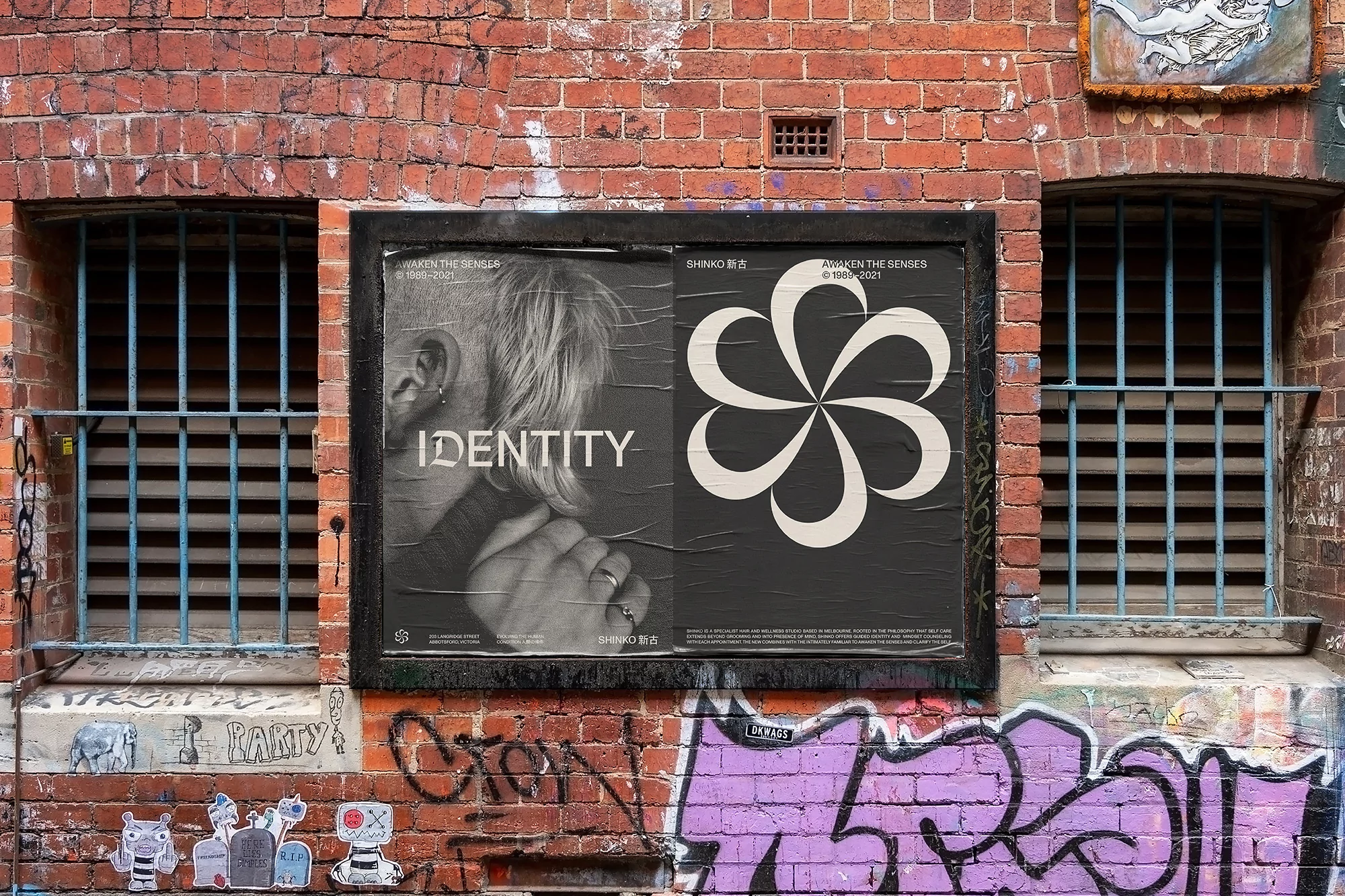 Gritty urban scene with a weathered brick wall featuring graffiti and a black-framed poster for 'Identity' next to barred windows.