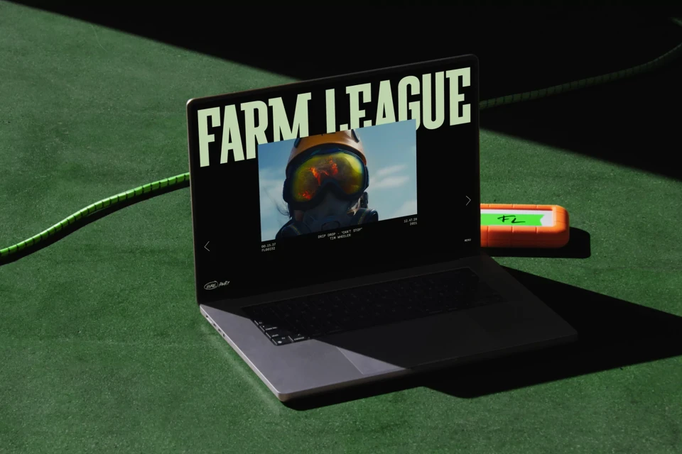 Laptop displaying a video of a person wearing a helmet, sitting on a green surface with a hard drive, illuminated by studio lighting.