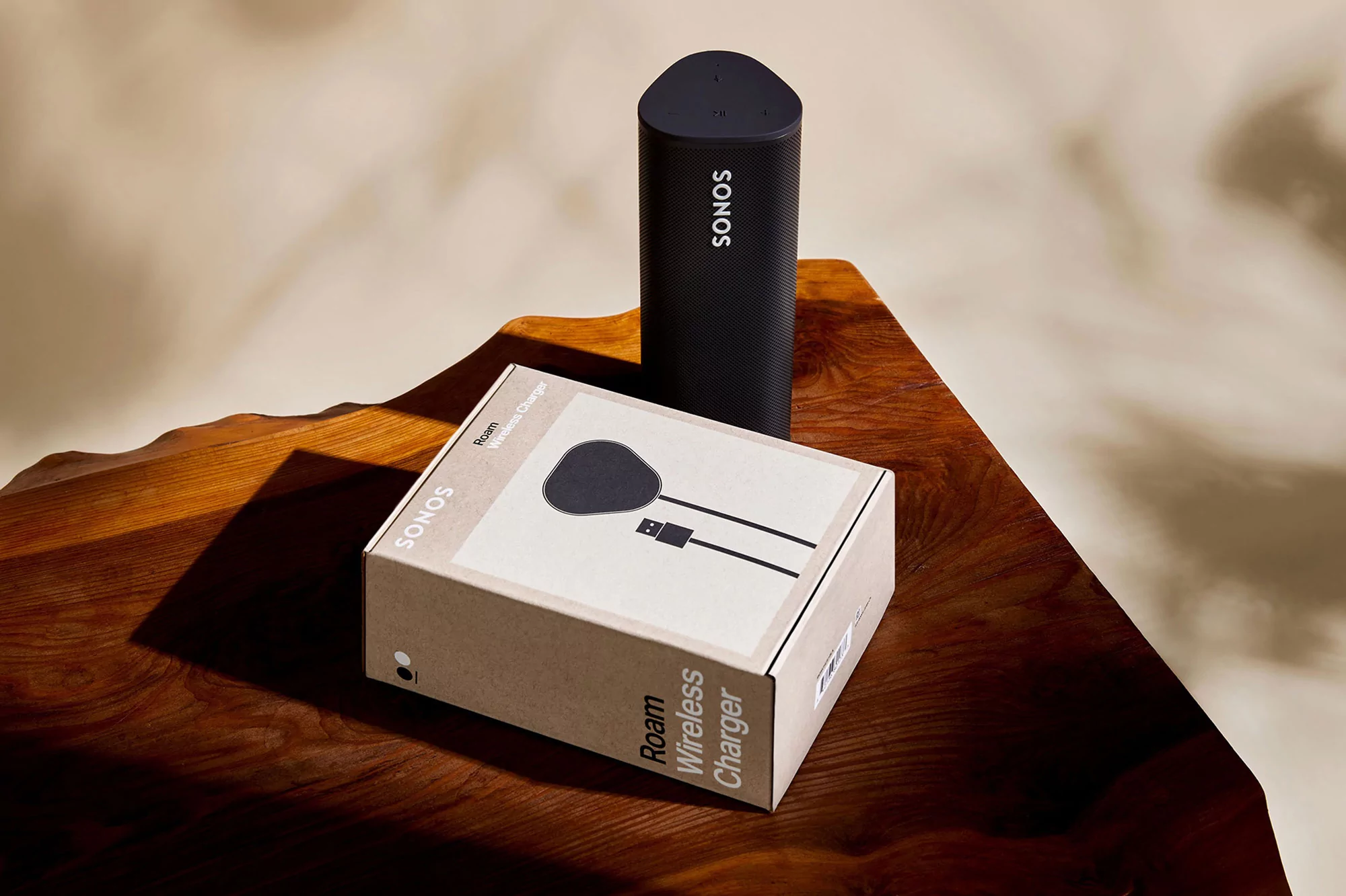 Sonos speaker and Roam Wireless Charger box sitting on a wooden surface, product photography, studio shot, simple clean background.