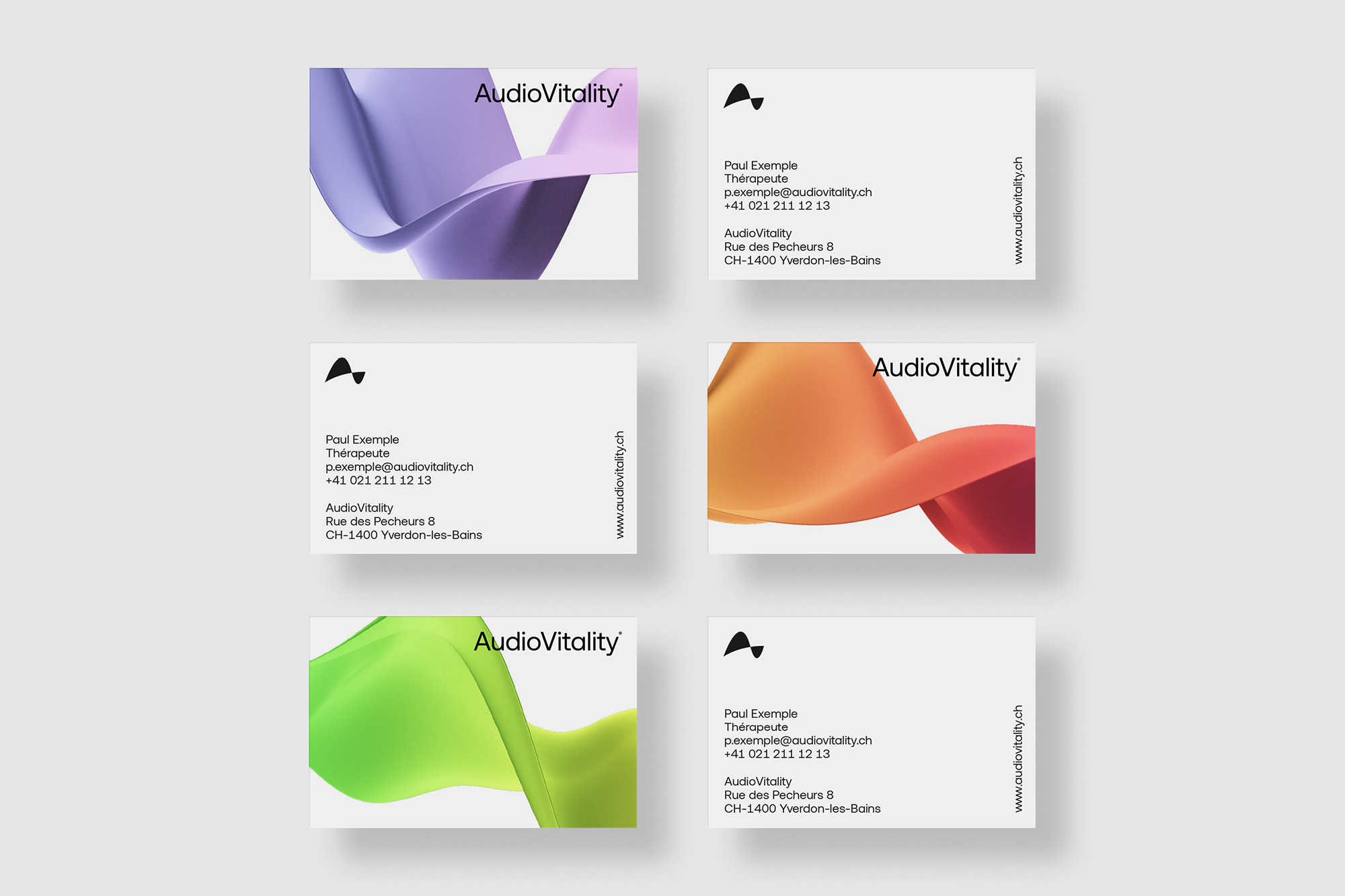 Several business cards with the brand AudioVitality sit on a white surface with flowing colored graphics and contact information.