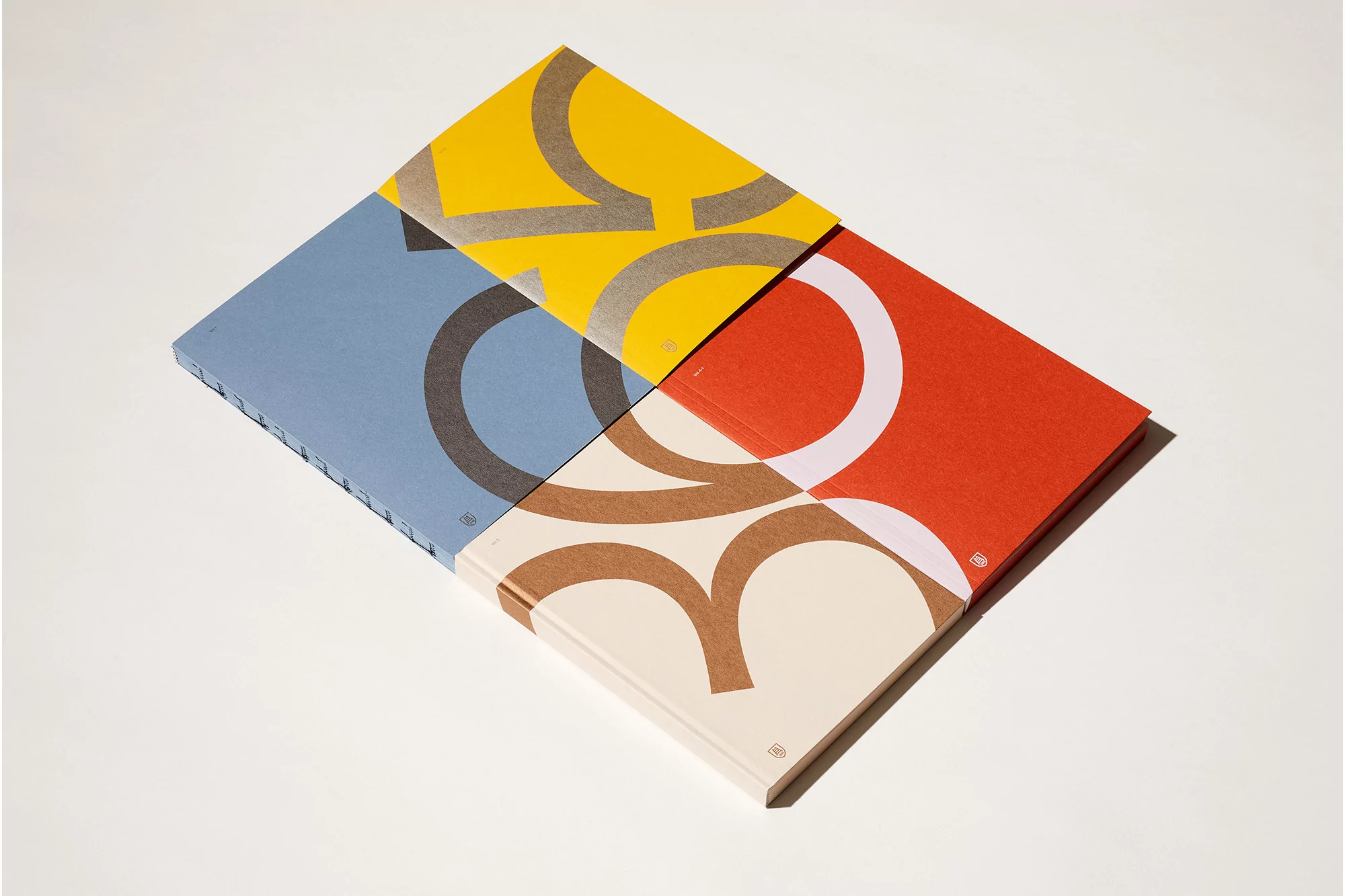 Overhead view of four colorful notebooks stacked together, each with a geometric design on a bright white background, flat lay.