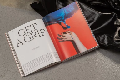 Open magazine page displaying bold typography reading Get a Grip alongside a hand reaching toward a blue balloon on red background