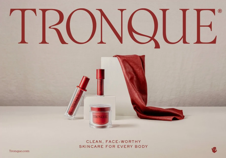 Cosmetic product photoshoot featuring Tronque skincare products in red and clear packaging with a red cloth accent on a white surface.