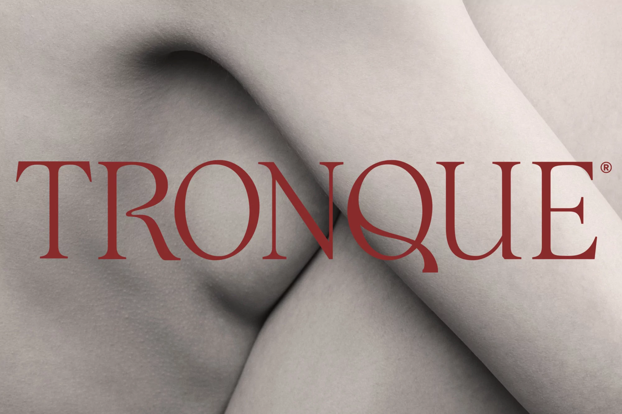 Close-up of a fair-skinned person's upper torso with a red, sans-serif logo reading TRONQUE across the center of the composition.