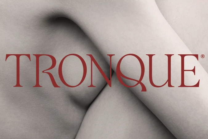 Close-up of a fair-skinned person's upper torso with a red, sans-serif logo reading TRONQUE across the center of the composition.
