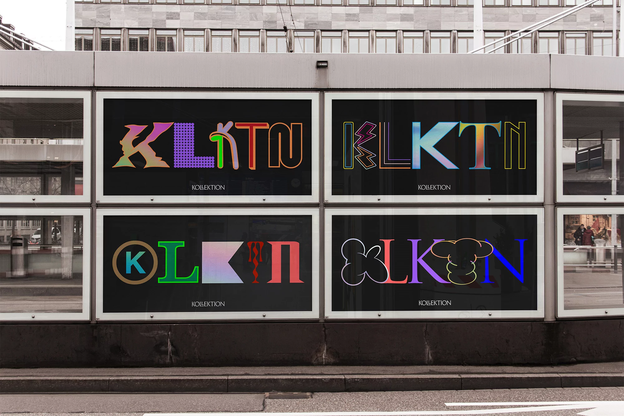 Outdoor advertisement on a bus stop featuring colorful, abstract text designs against a black background on an overcast day.