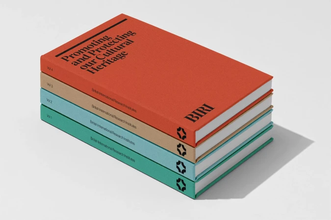 Stack of four textured hardcover books in orange, beige, light blue and green with black text, set against a white backdrop.