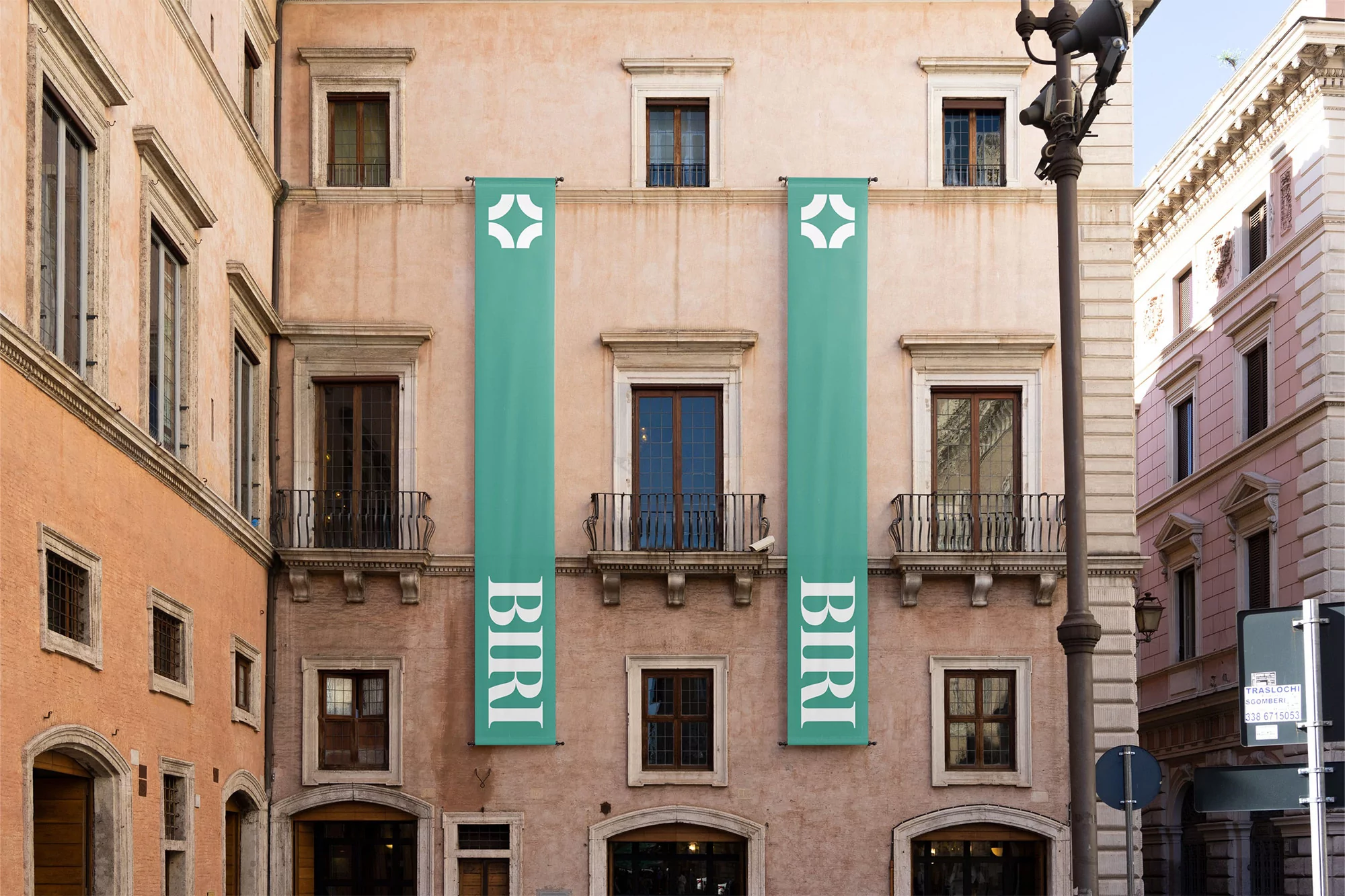 Exterior of a building with symmetrical architecture, windows, arched doorways, and two banners with the word 'BIRI' hanging vertically.