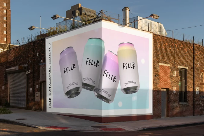 Outdoor advertising features colorful FELLR cans on a building corner against a clear sky, promoting the brand's alcoholic seltzer.