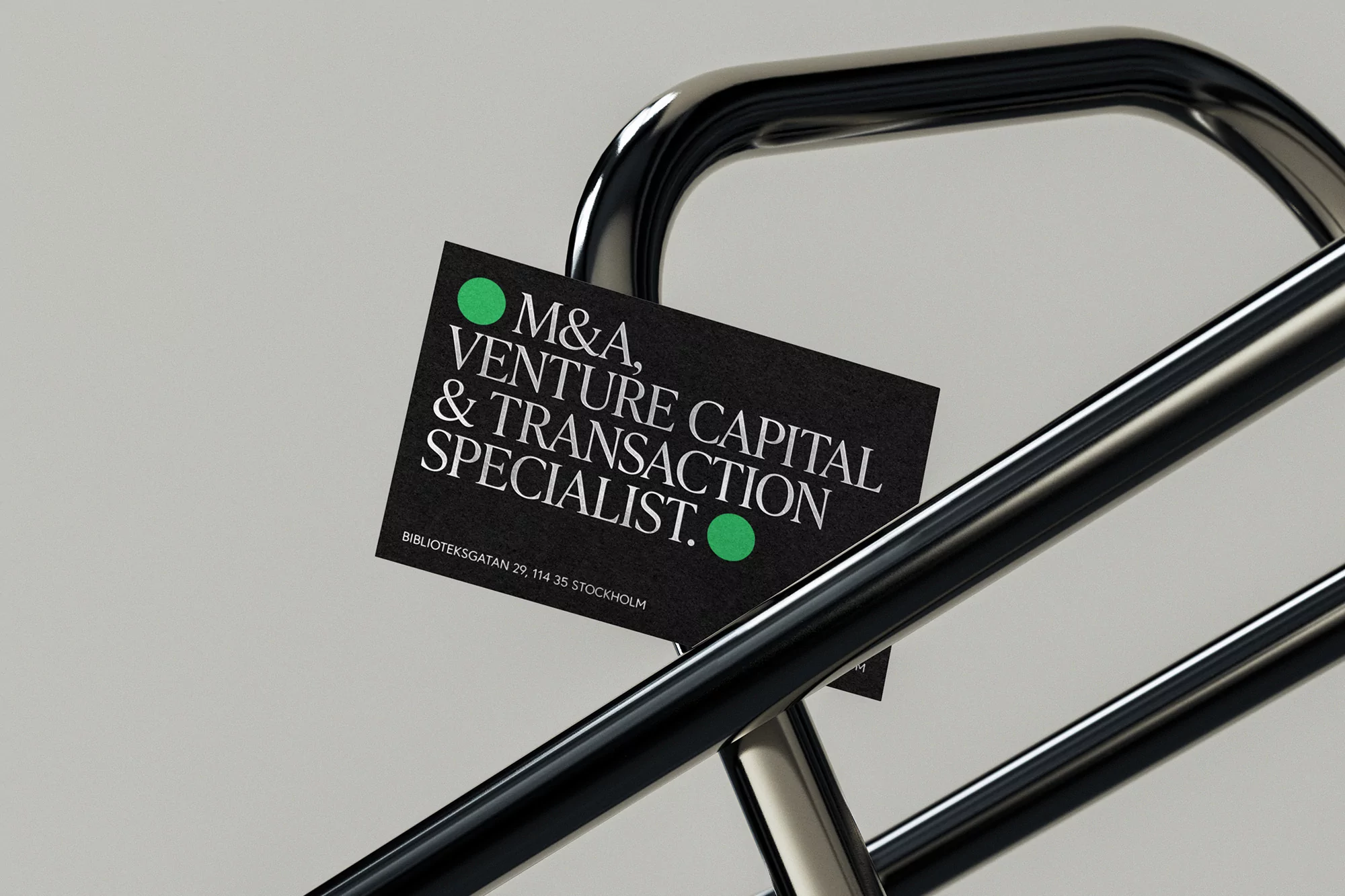 Business card for M&A, venture capital, and transaction specialist, with green dot accents on dark background, displayed on metal railing.