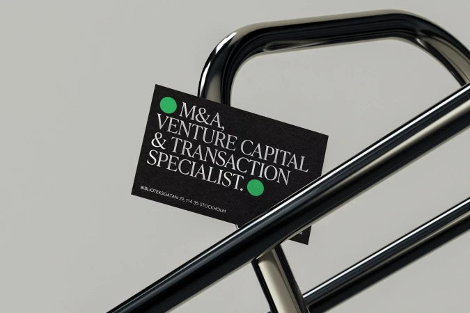 Business card for M&A, venture capital, and transaction specialist, with green dot accents on dark background, displayed on metal railing.