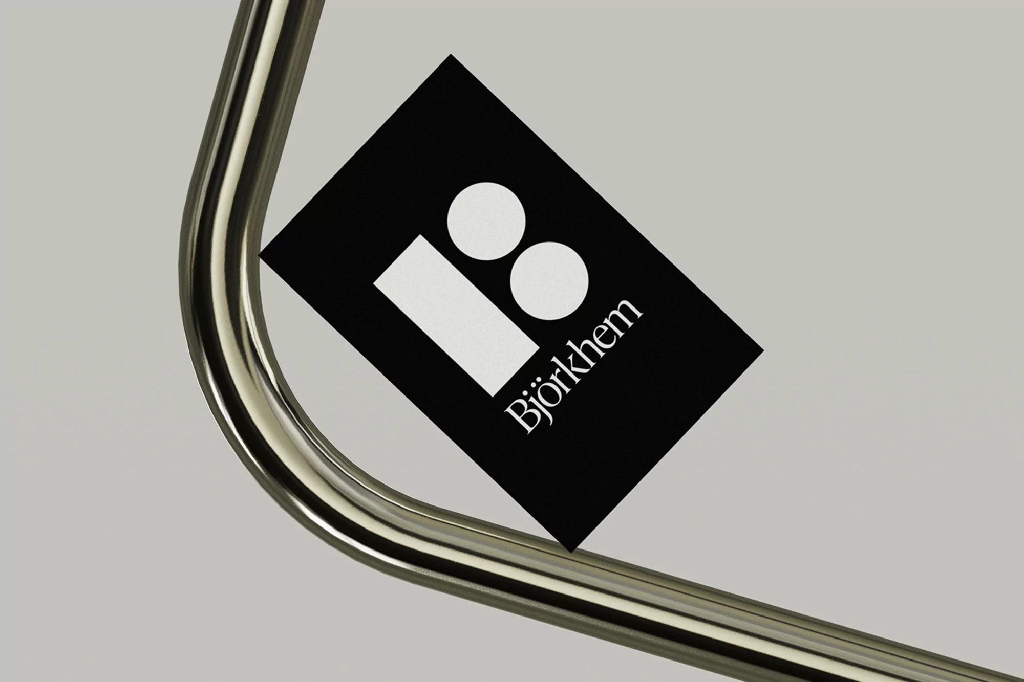 A product shot showcasing a black card with a white logo and the text "Björkhem," resting on a metal tube against a neutral background.