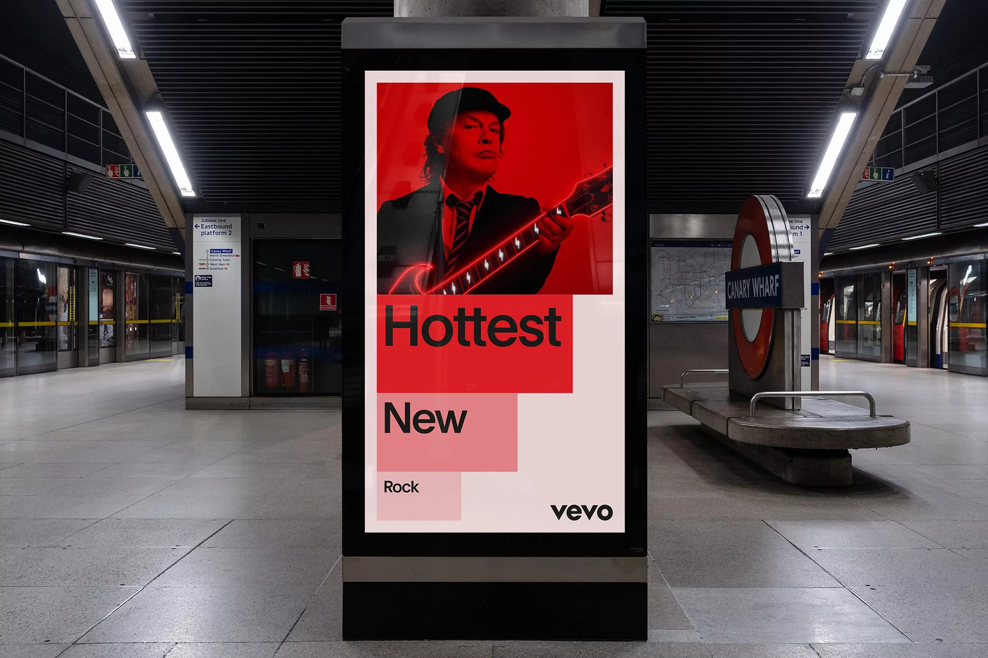 Advertisement in a subway station featuring a musician with a guitar and bold text promoting new rock music on Vevo.