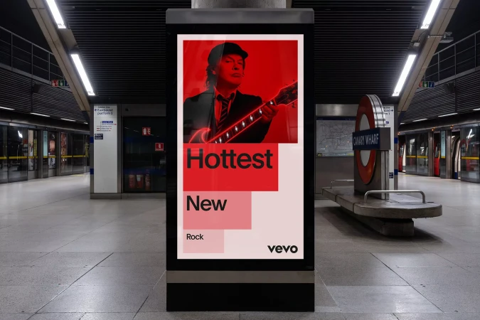 Advertisement in a subway station featuring a musician with a guitar and bold text promoting new rock music on Vevo.