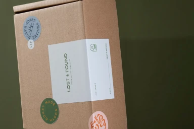 Cardboard shipping box branded with Lost and Found labels against a solid green background