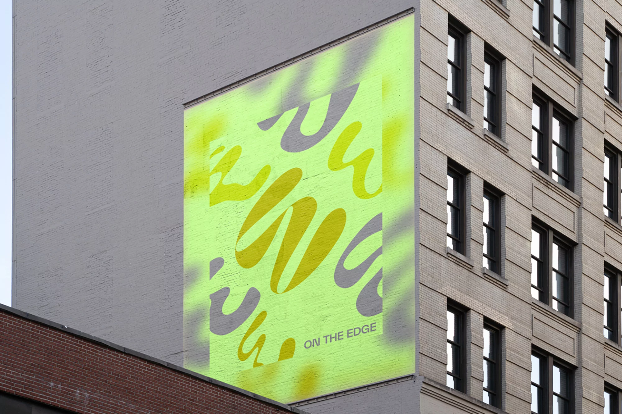 Exterior shot of building with abstract mural art with yellow and gray designs painted on side of a brick building.